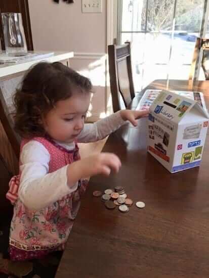 A little girl counting a few coins on the table